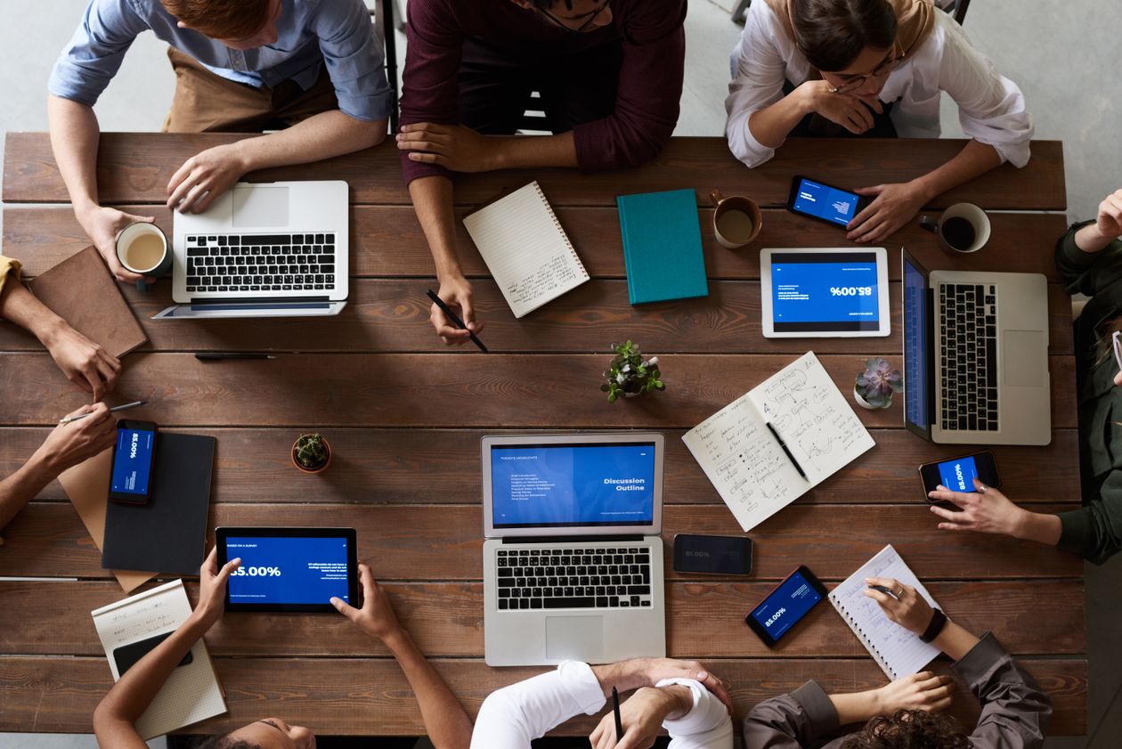 Business professionals collaborating around a table with laptops and documents in a modern office setting