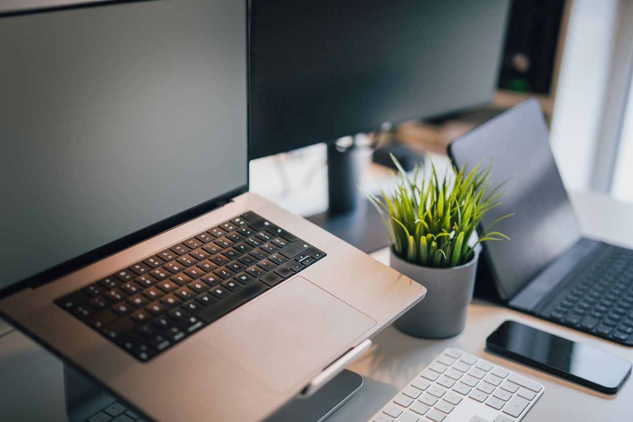 Sleek office workspace with laptop, smartphone, keyboard, and plant — Microsoft 365 business technology theme