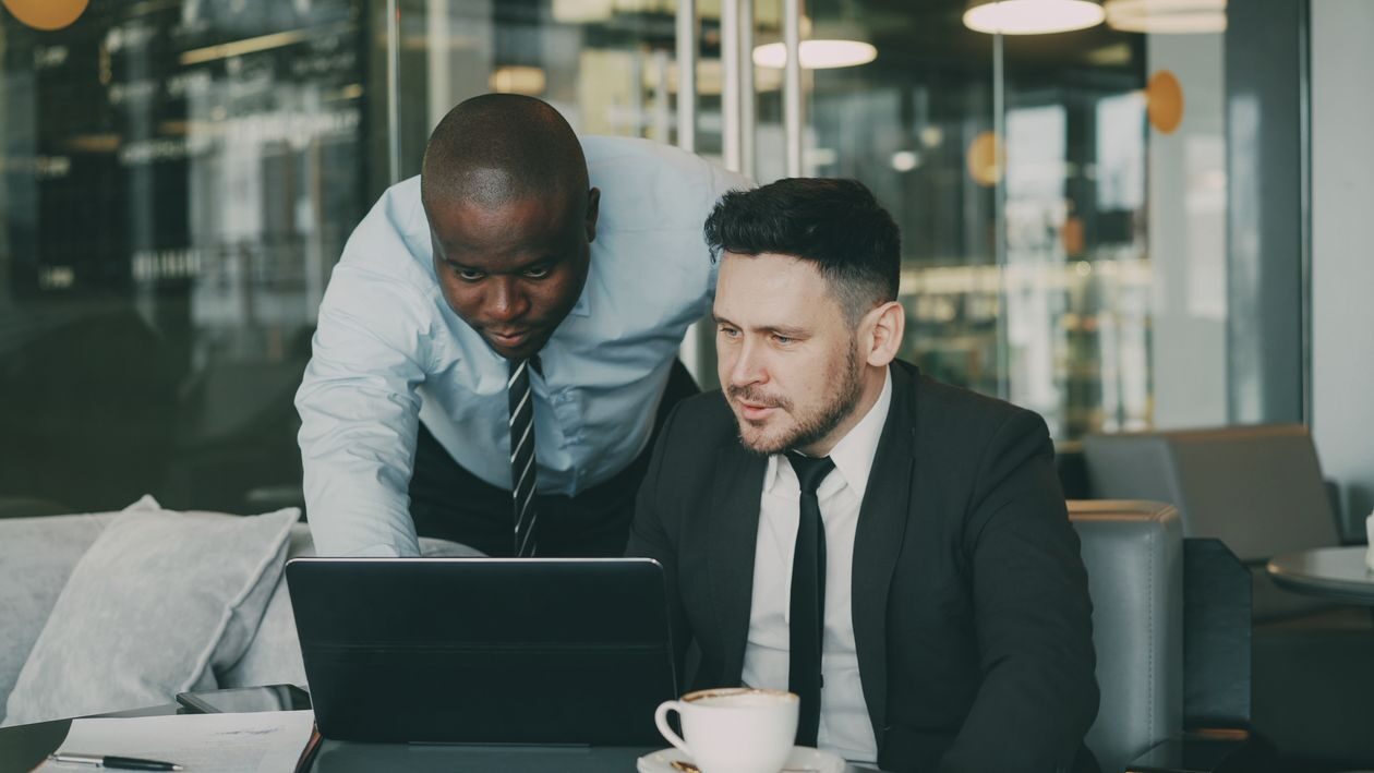 Two business professionals collaborating over a laptop in a modern office