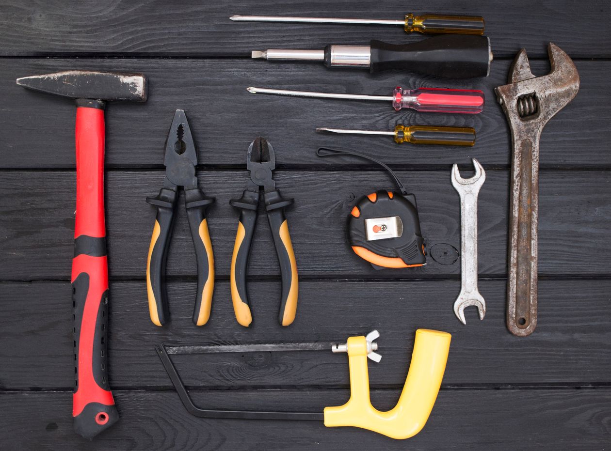Flat lay of various hand tools on a black wooden surface